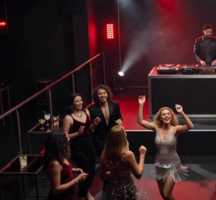 Színes színpadi fényekkel megvilágított DJ pult és tánctér